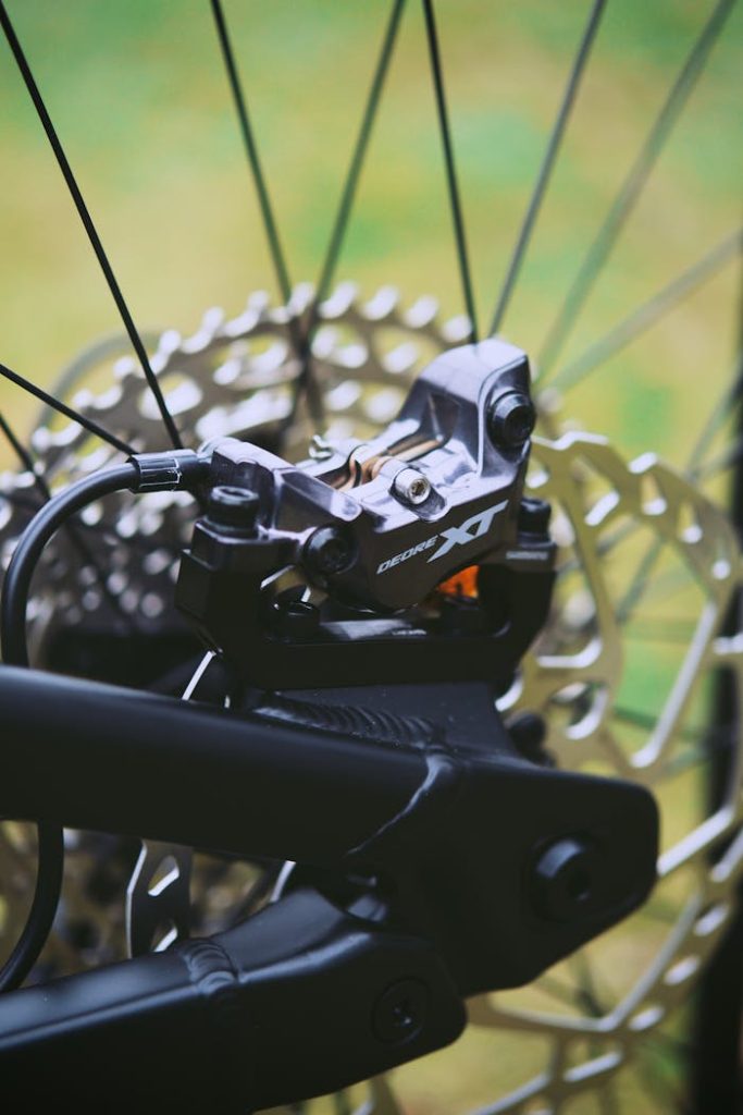 a-close-up-shot-of-a-brake-caliper-of-a-bike-7285839 Detailed view of a mountain bike braking system showcasing the disc and caliper in focus.