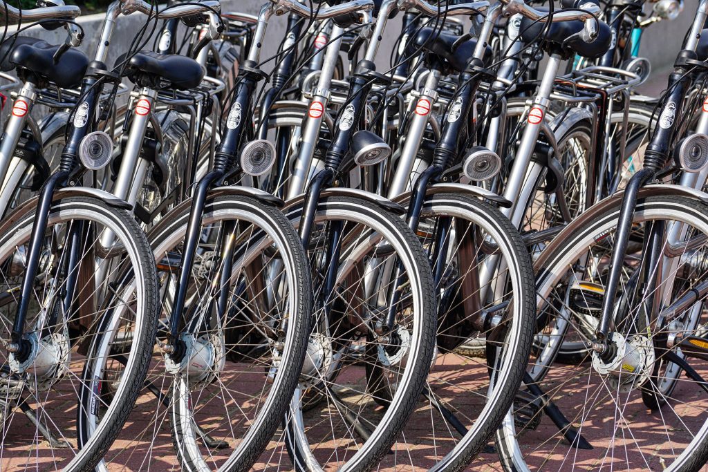 A detailed view of multiple bicycles parked in an outdoor urban area, showcasing wheels and handlebars.