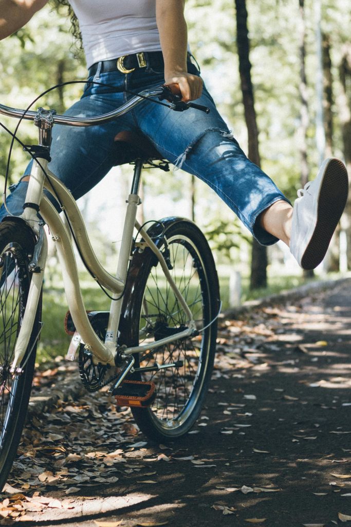 A woman enjoys a relaxing bike ride through a sunlit park path.
